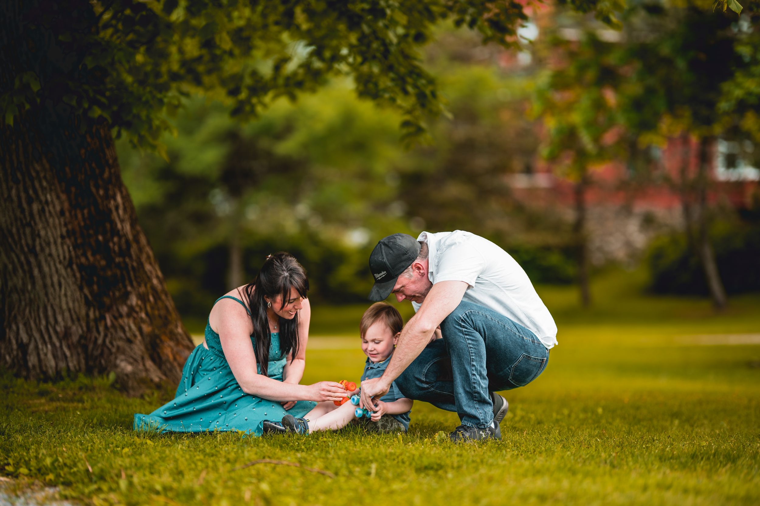 Family members laying on grass during casual outdoor photoshoot.