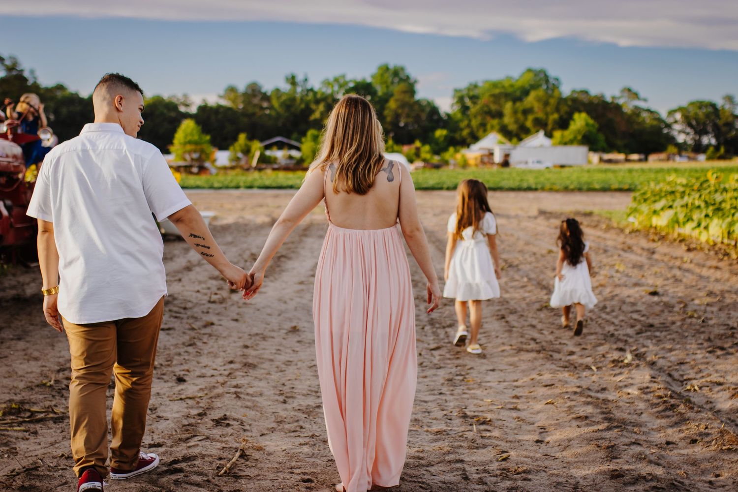 A family walks hand in hand through a rural field at sunset.