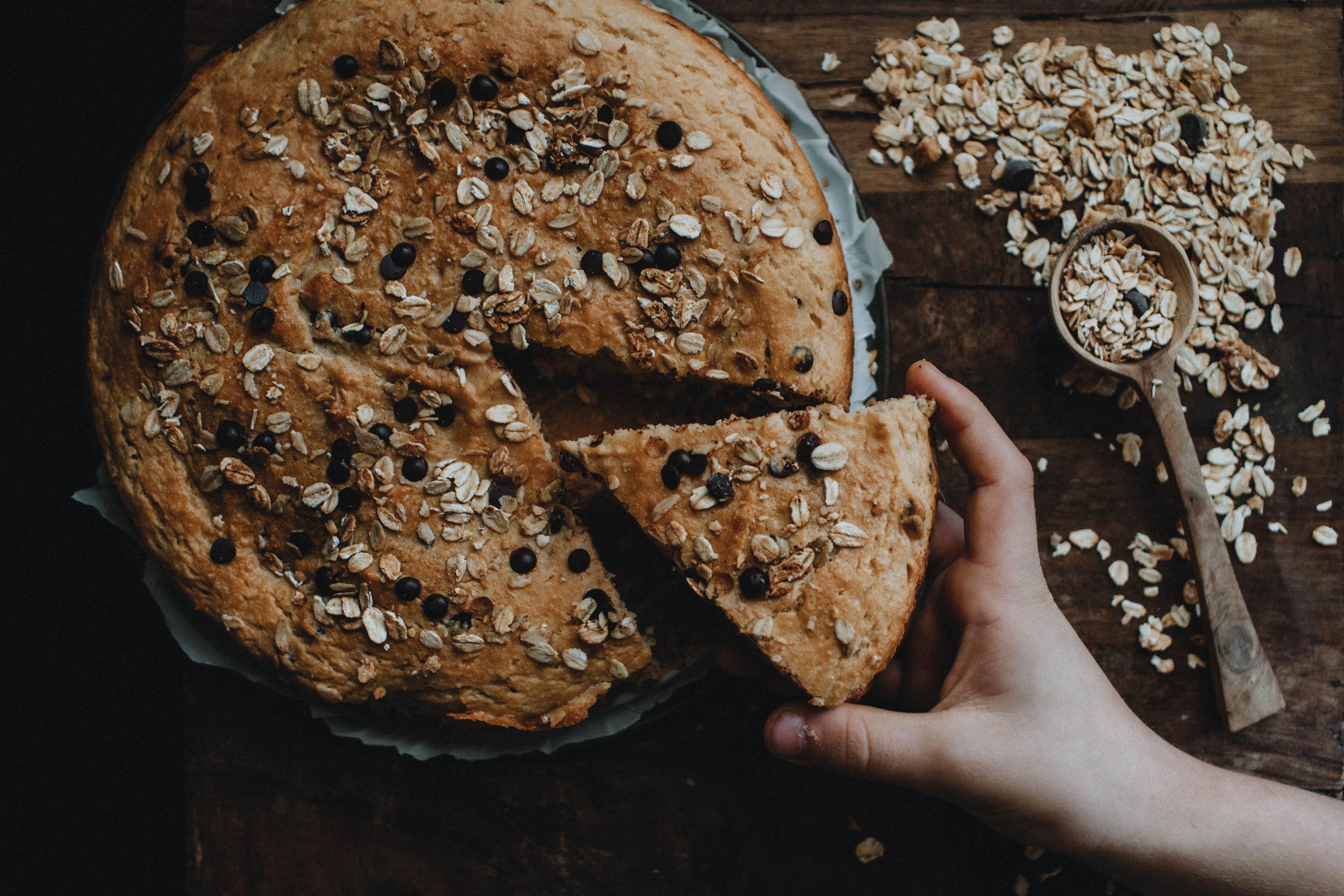 Candid photo of a child’s hand stealing oatmeal cake, illuminated by natural light, evoking moody and authentic childhood moments