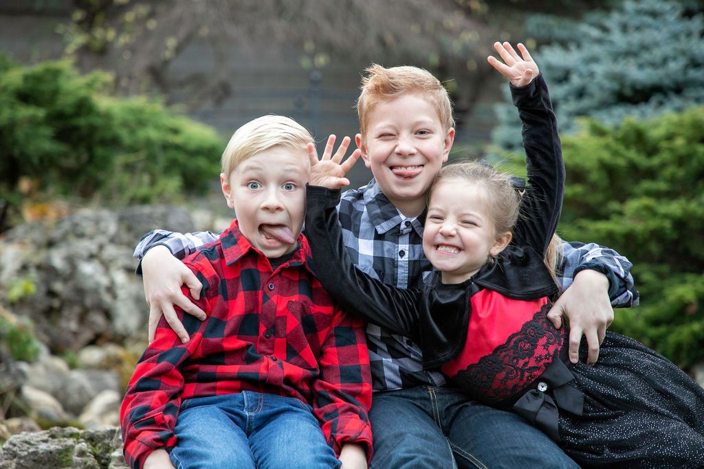 Three young kids at Oshawa Botanical gardens with the oldest boy in the middle wrapping his arms around his younger siblings