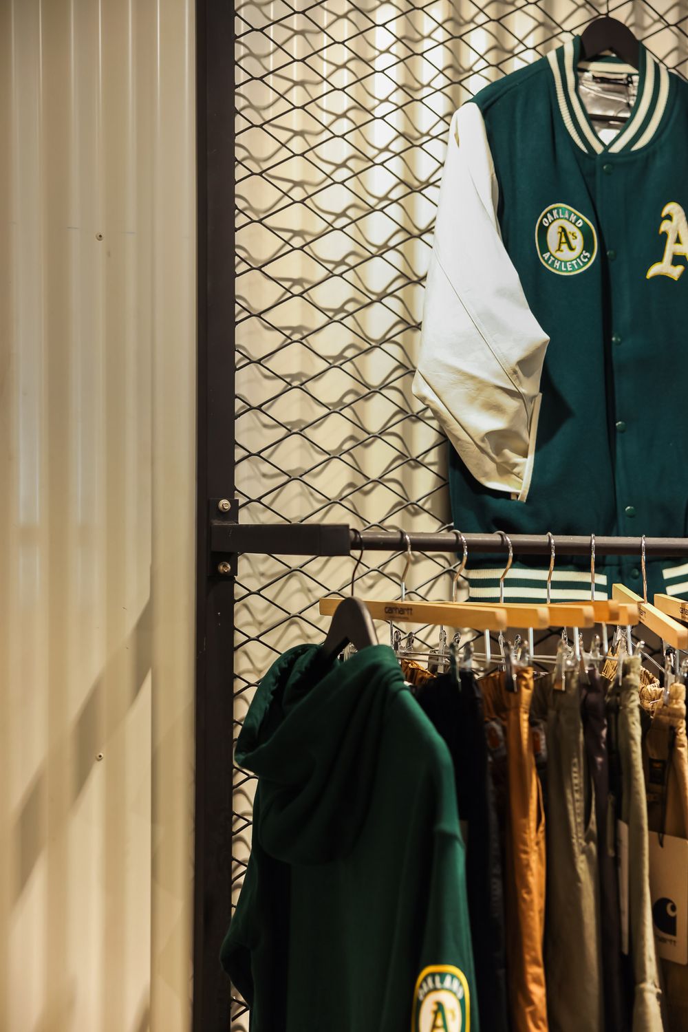 Display of green and white athletic jerseys and apparel hanging on retail clothing racks.