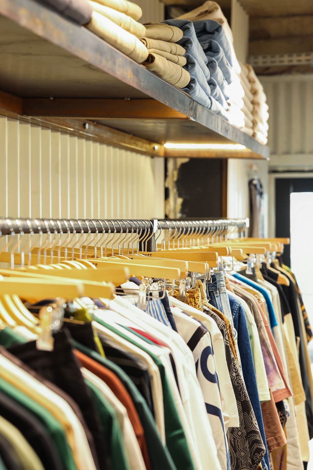 Long rack of vintage and second-hand clothing displayed in a thrift store.