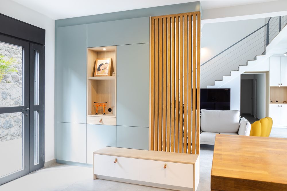 Contemporary living space with wooden slat accents and built-in storage along light blue walls.