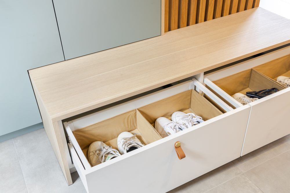 Built-in storage drawers with wooden handles against a light blue wall showing organized interior compartments.