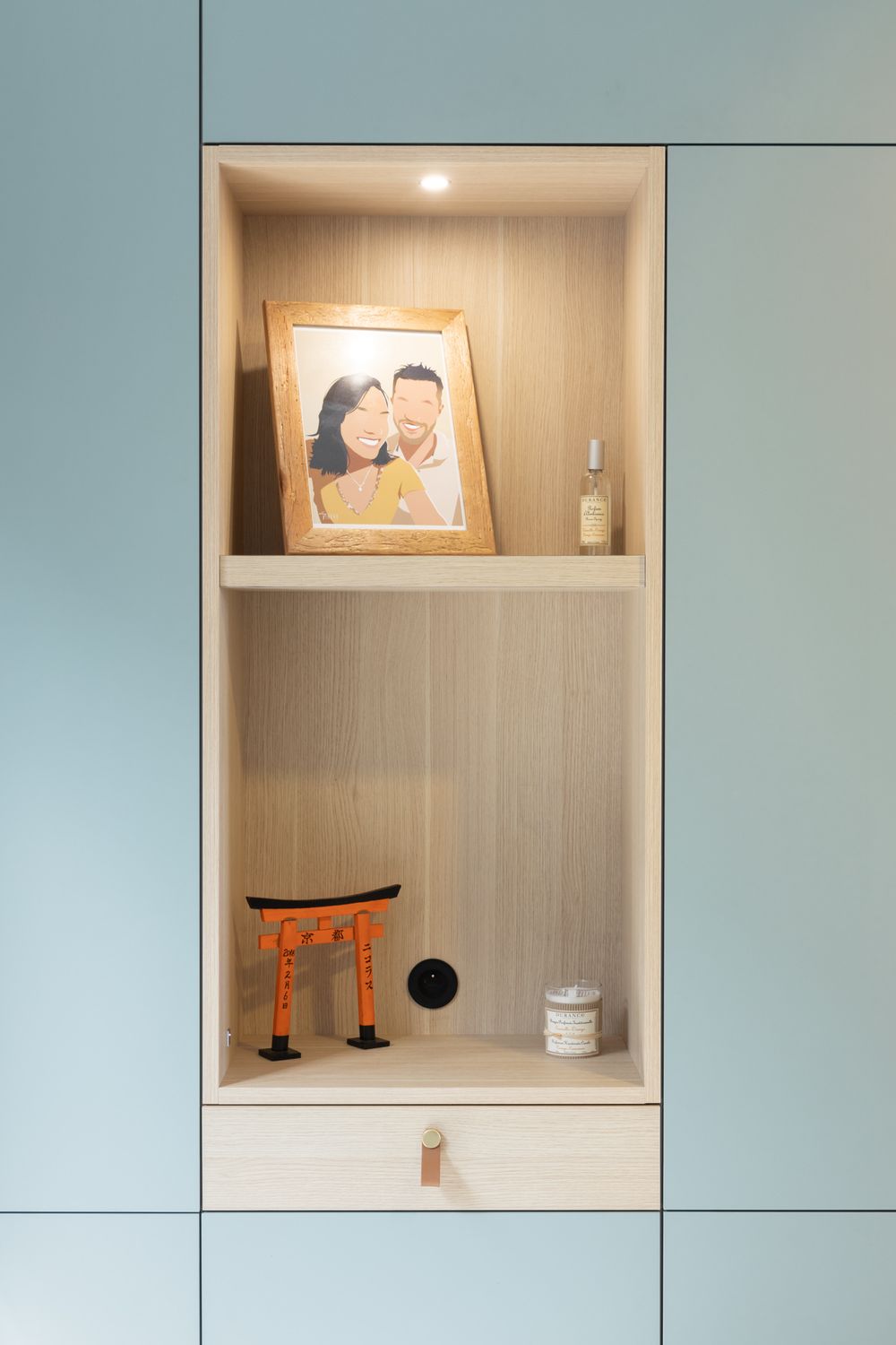 Modern wall unit with display niches featuring decorative objects against a soft blue background.