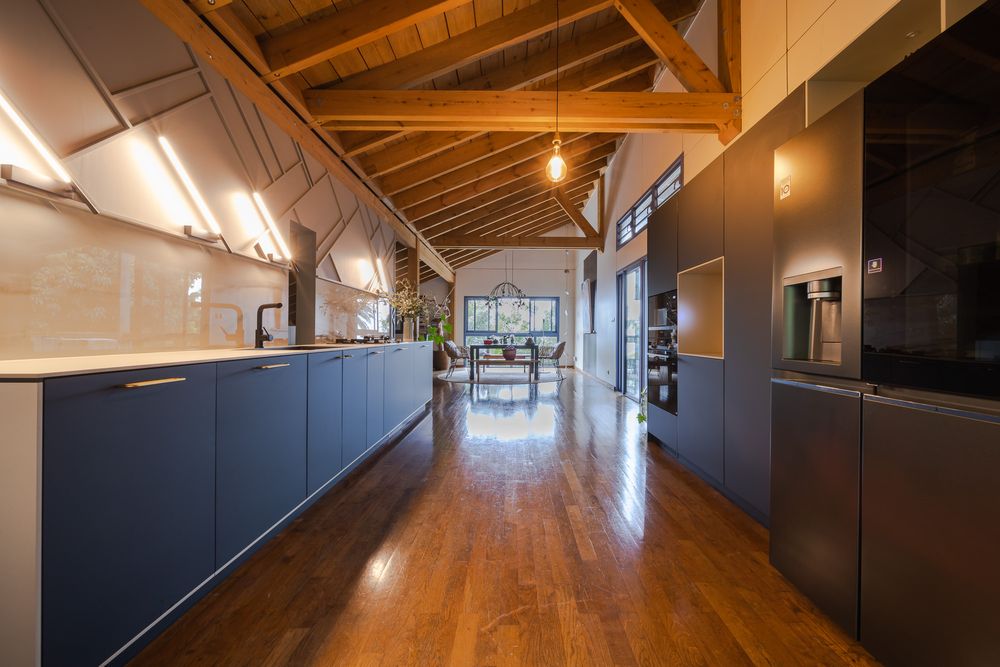Long hallway with wooden ceiling beams and dark modern cabinets along the wall.