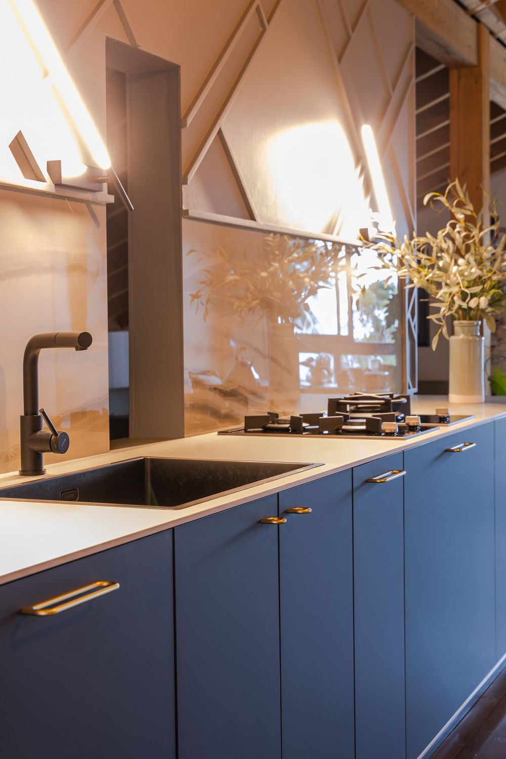 Contemporary kitchen design featuring navy blue cabinets and white countertops under wooden beams.