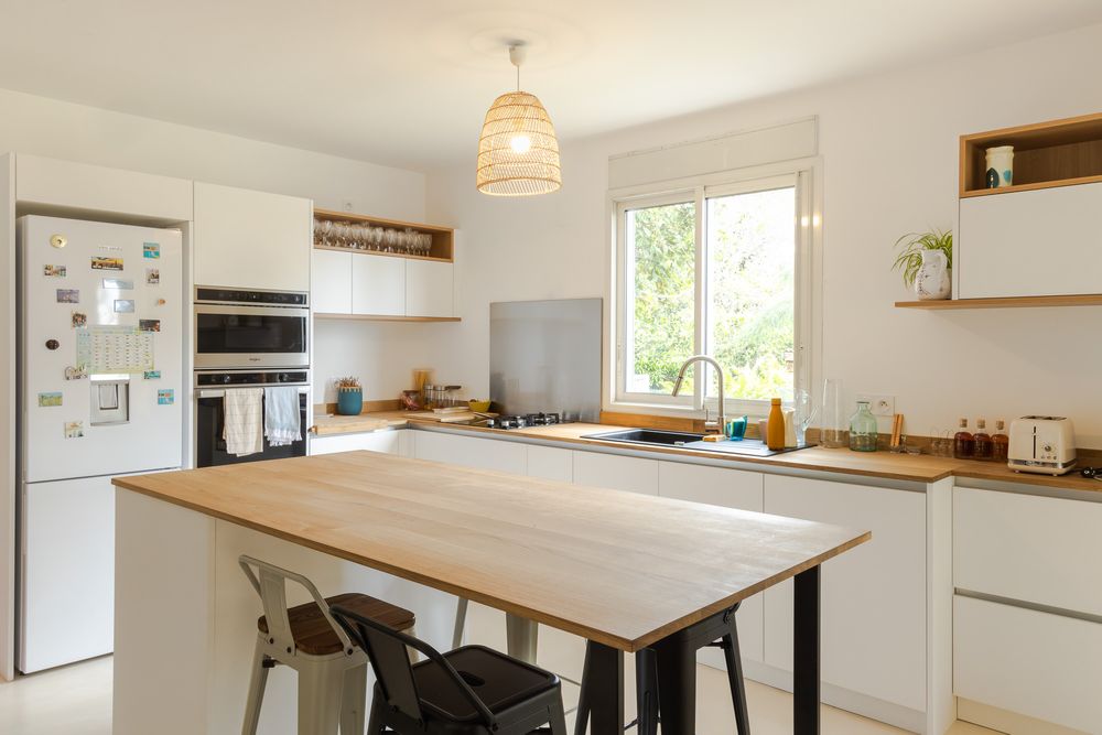 Bright open-concept kitchen featuring white cabinets, wooden countertops and a central dining area.