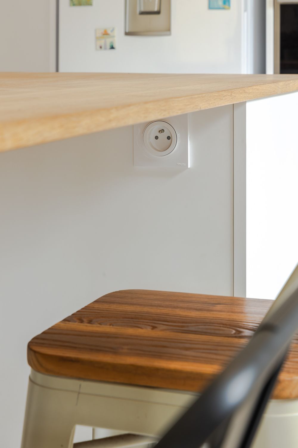 Close-up detail of wooden dining surface and modern chair in contemporary kitchen setting.