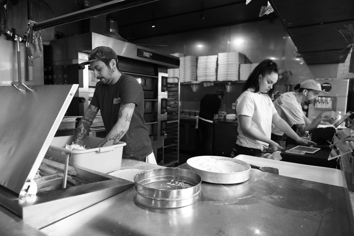 Kitchen staff working in a busy commercial restaurant kitchen preparing food.