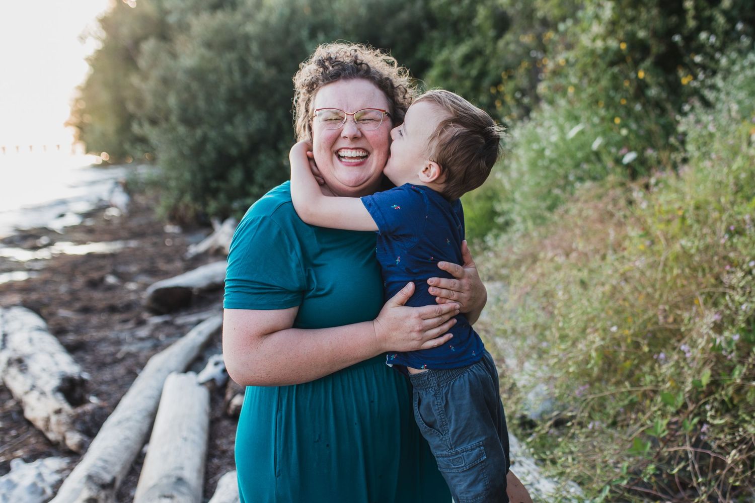 Little boy gives his mom a kiss while she smiles for family photos