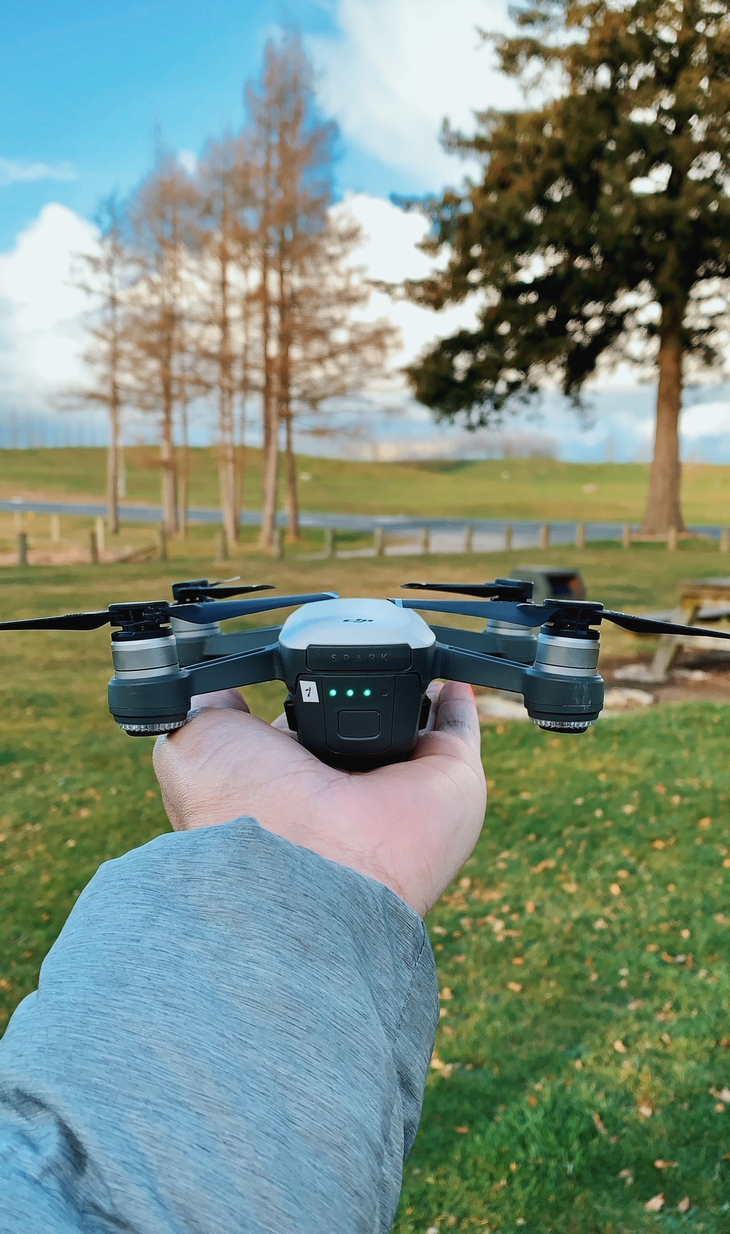 A small drone being held in hand against a backdrop of autumn trees and grass.
