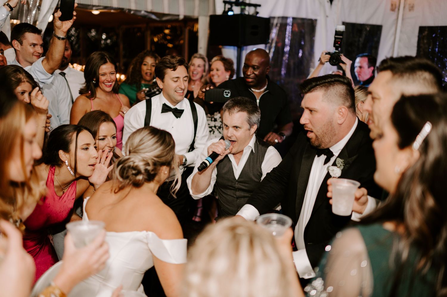 Lively dance floor scene at a wedding reception with guests celebrating in formal attire.