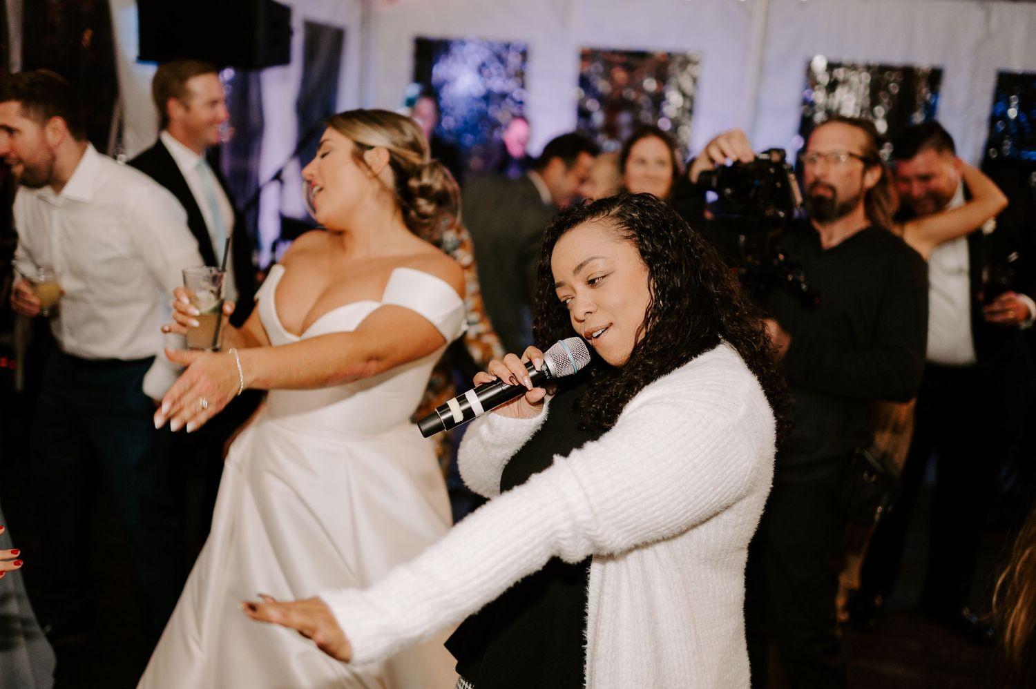 Wedding party members dance and celebrate together at a dimly lit reception.