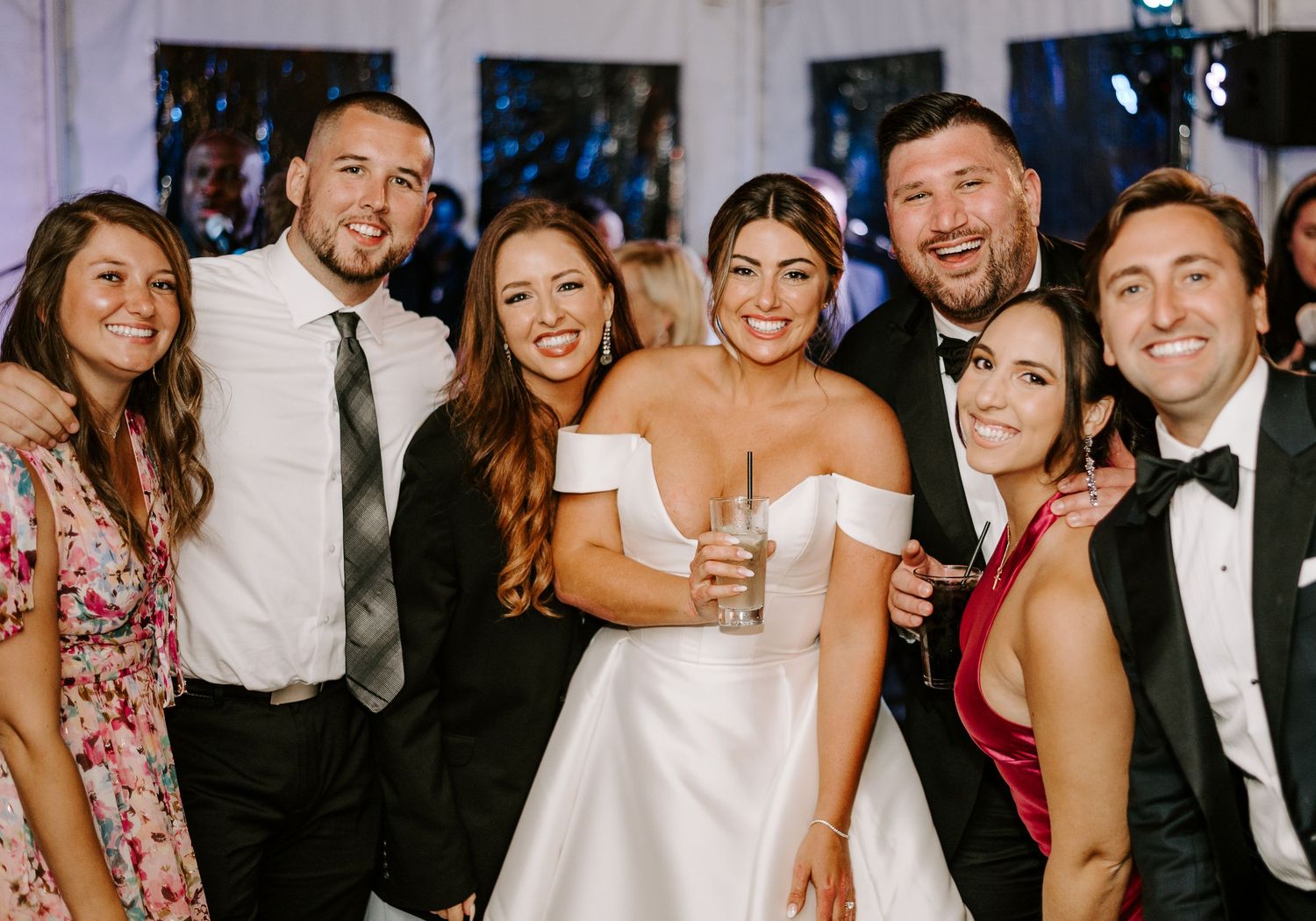 Wedding guests dancing and celebrating in formal attire under indoor lighting.