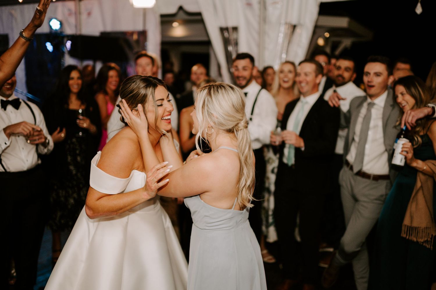 Wedding celebration with guests dancing and embracing on a crowded dance floor.
