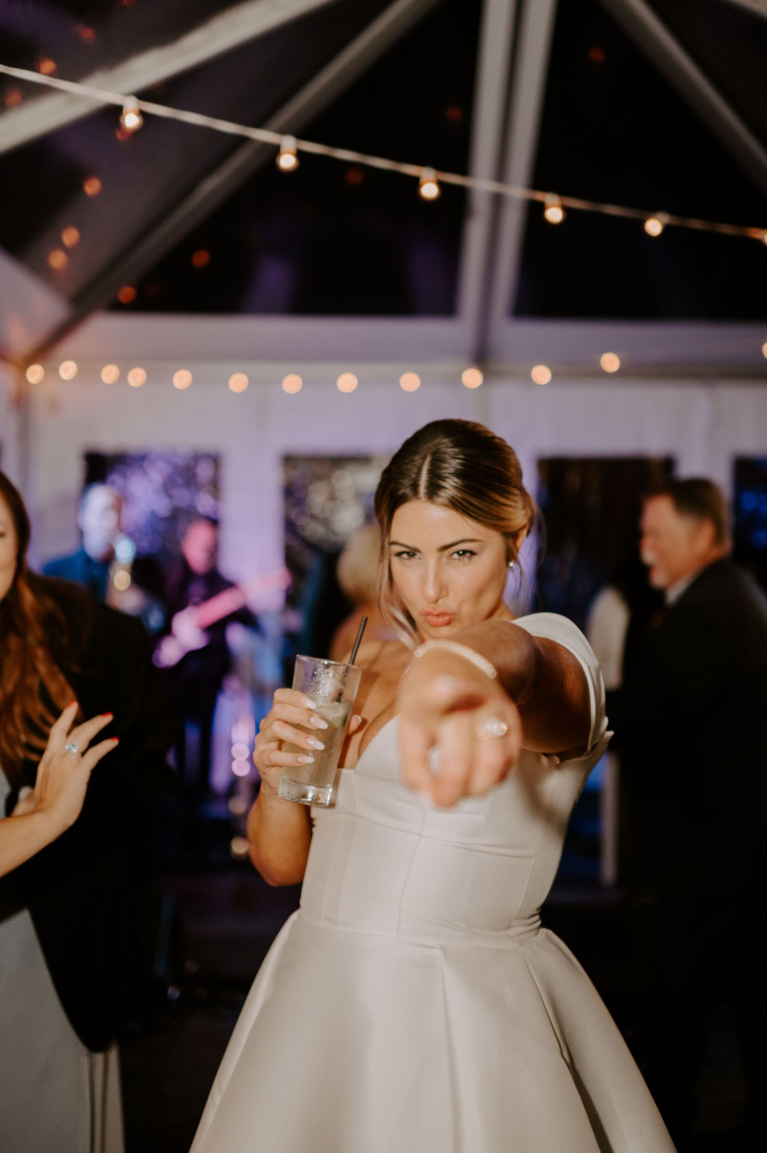 Person in a white wedding dress strikes a playful pose on the dance floor.