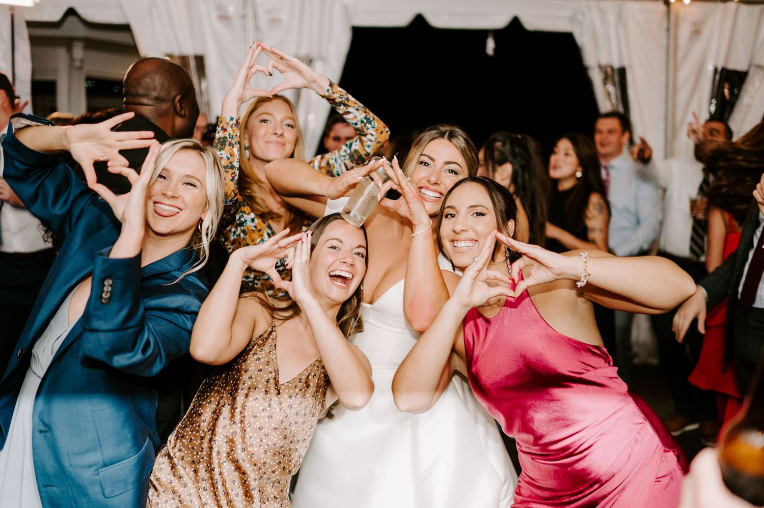 Wedding guests dancing and celebrating together under string lights at an evening reception.