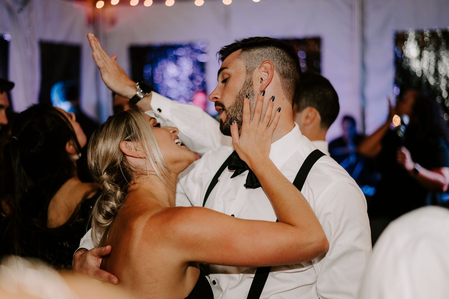Wedding reception dance floor filled with guests celebrating under string lights.