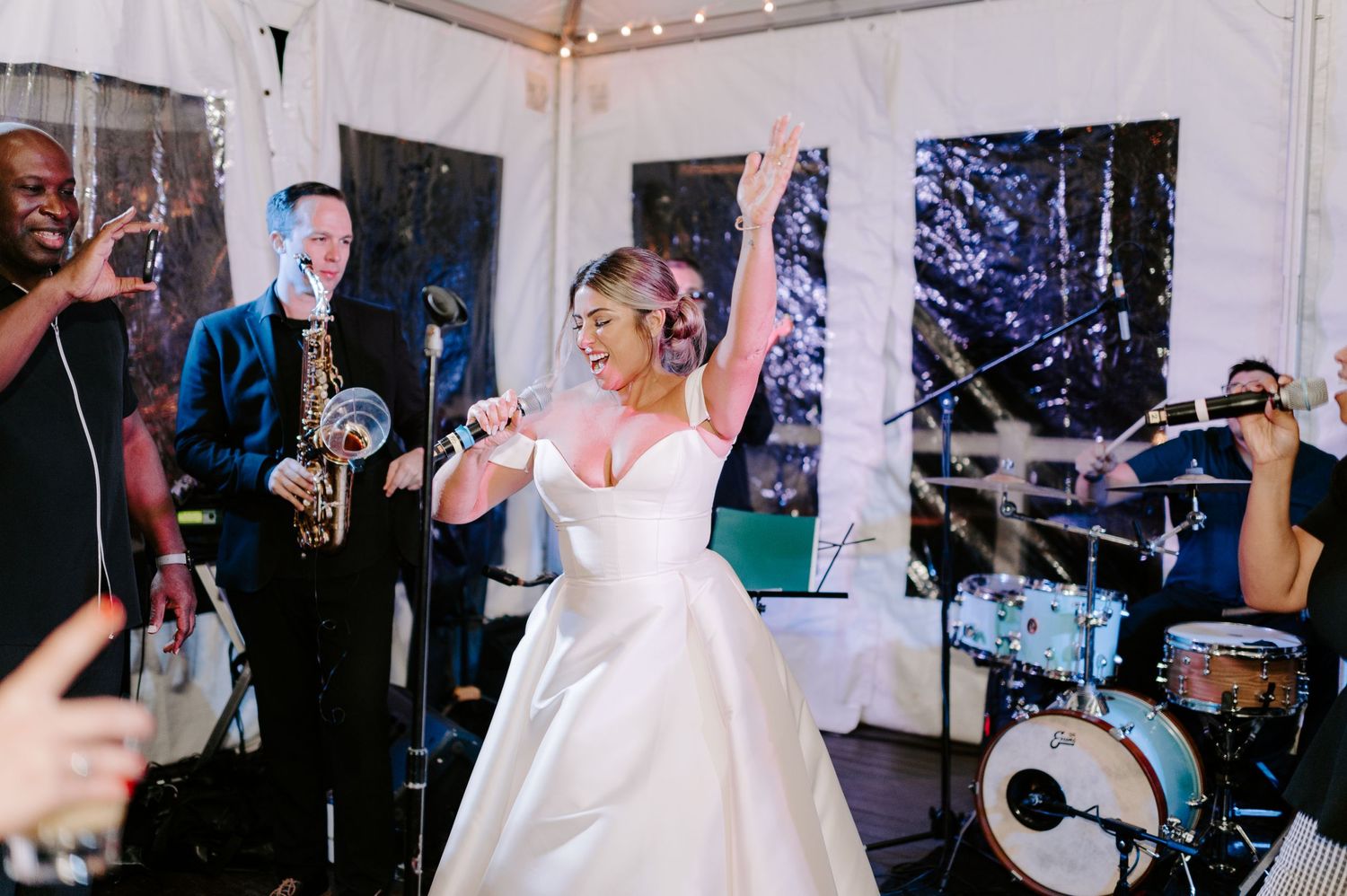 Wedding reception dance floor with string lights and white tent draping visible overhead.