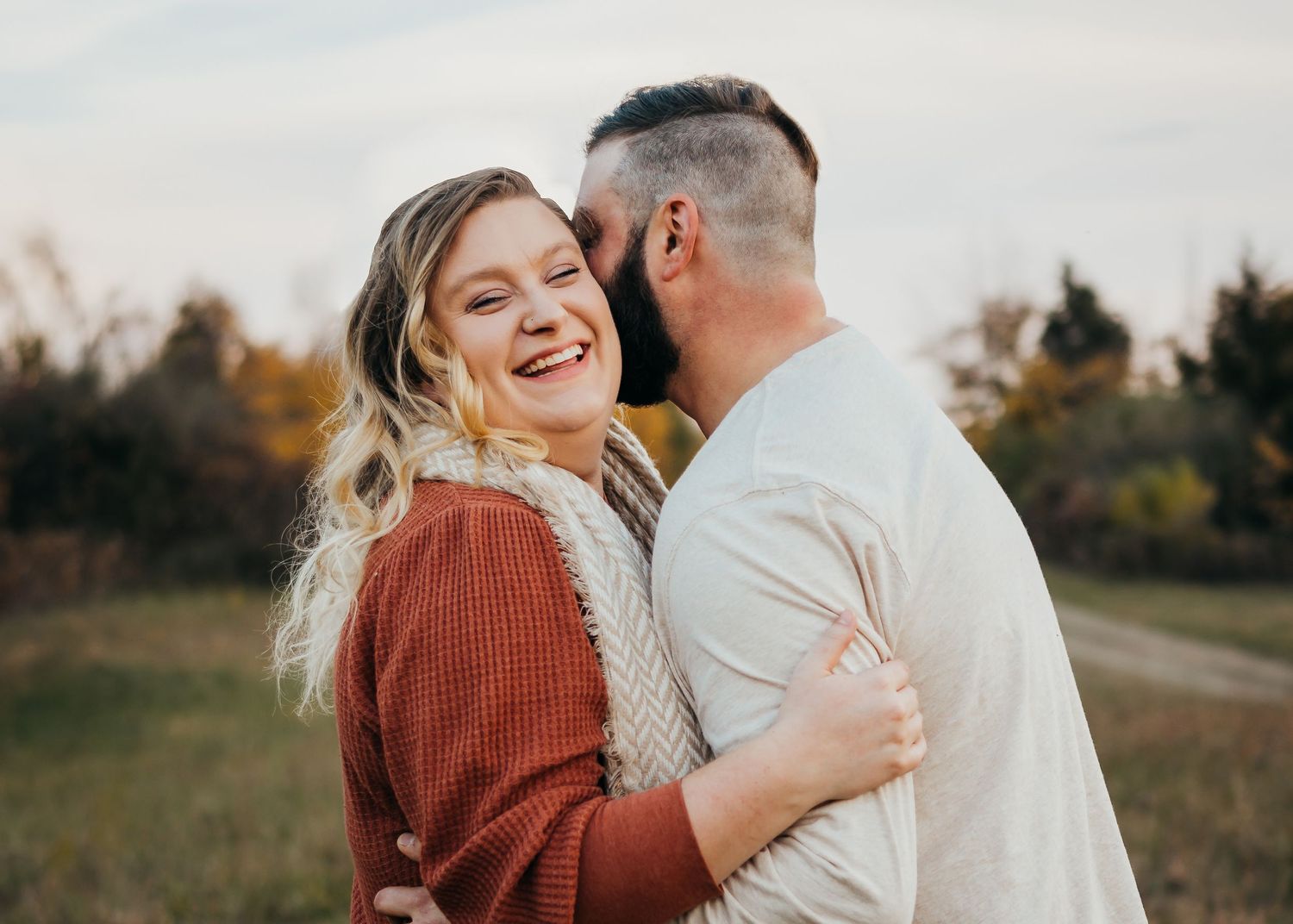 Candid moment of a couple laughing together during an autumn photoshoot.