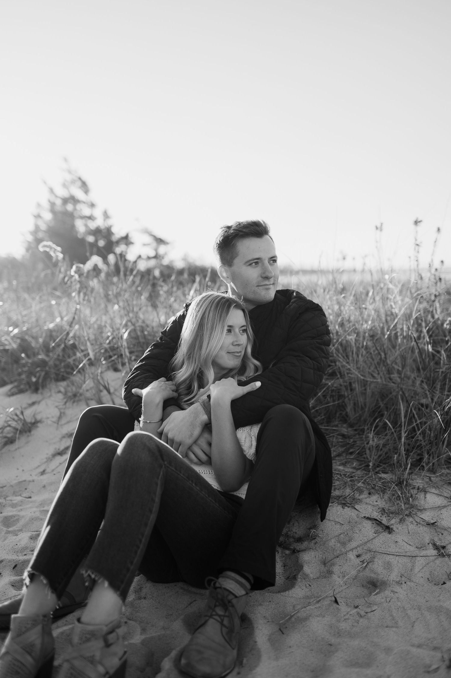 Black and white photos show a couple relaxing together on a sandy beach dune.