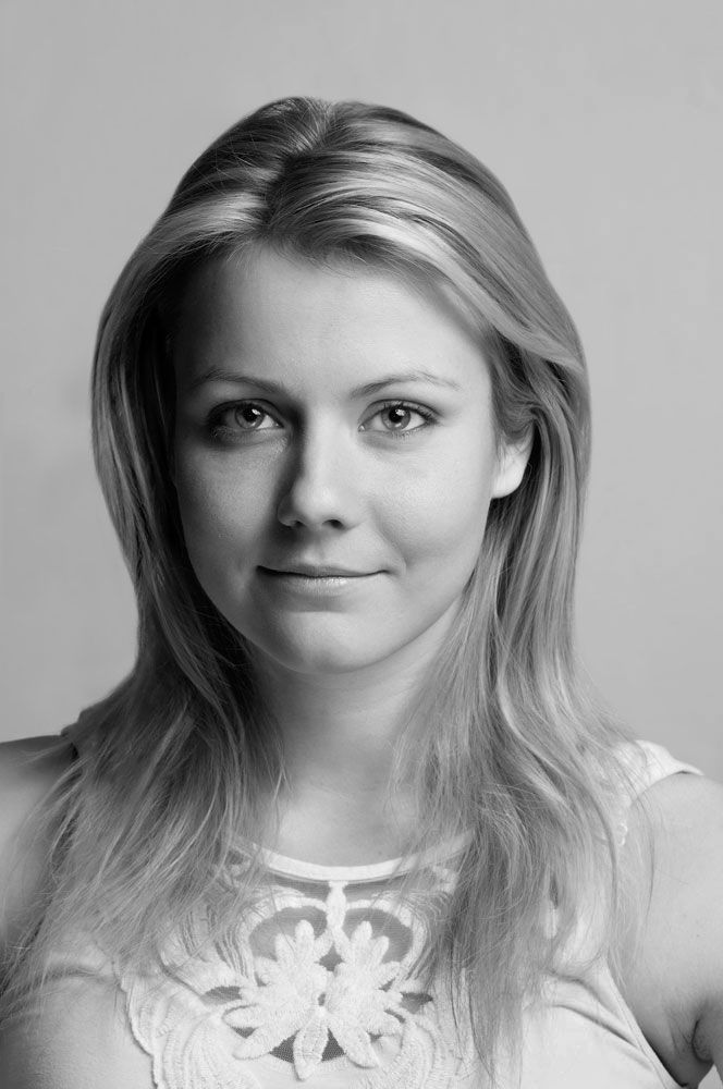 Black and white portrait of a blonde woman with long hair wearing a white lace top.