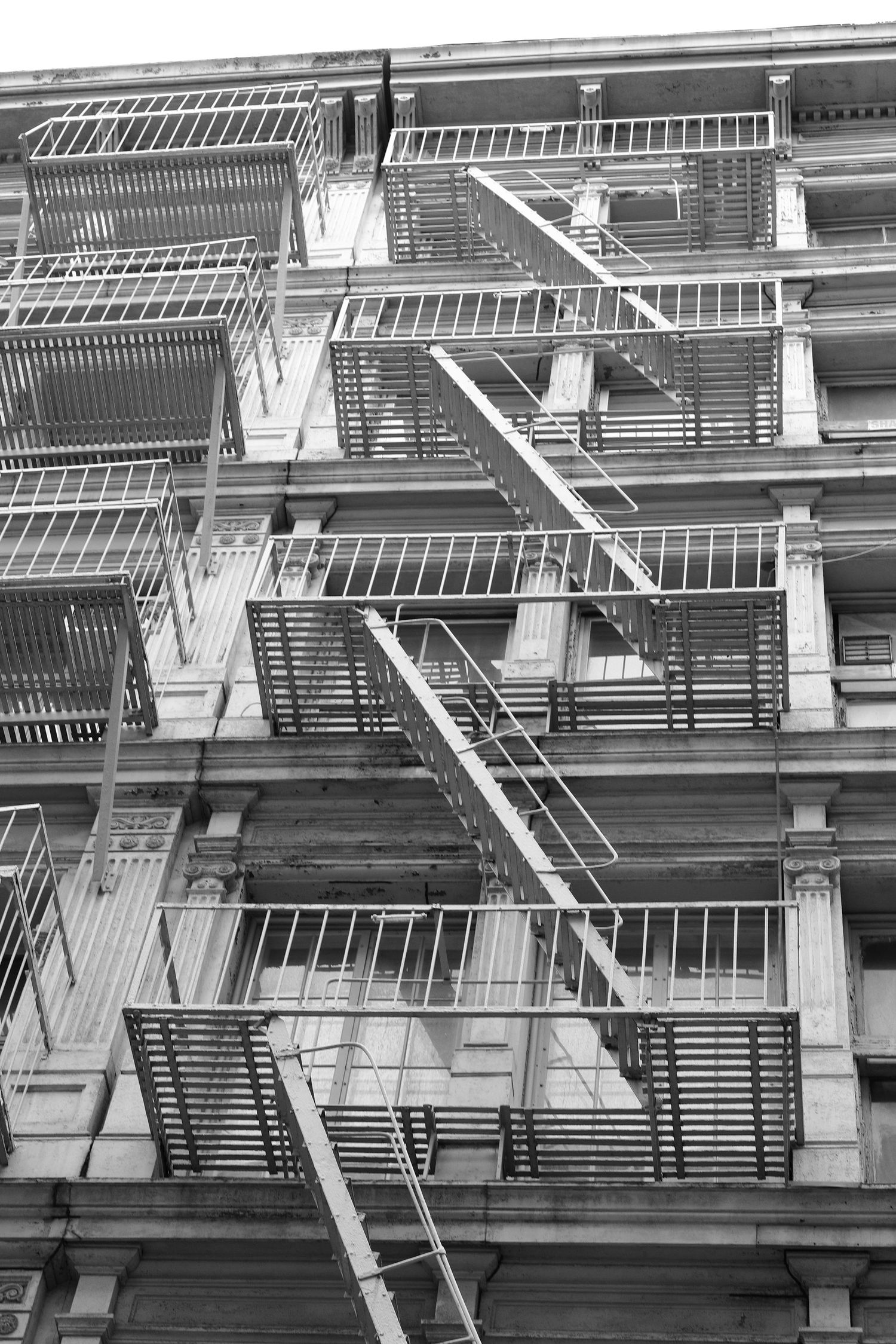 Geometric pattern of fire escapes on old apartment building exterior in monochrome.
