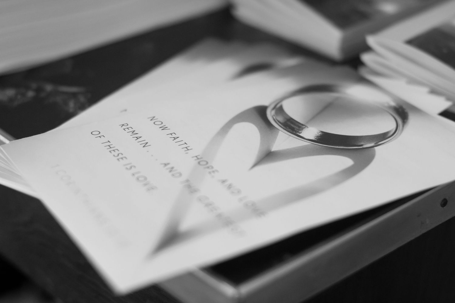 Wedding rings casting heart shadow on marriage certificate in black and white photography.