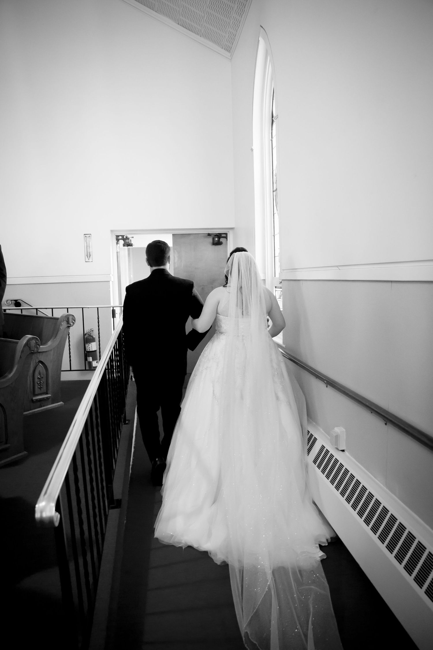 Black and white shot of couple descending church stairs after ceremony.