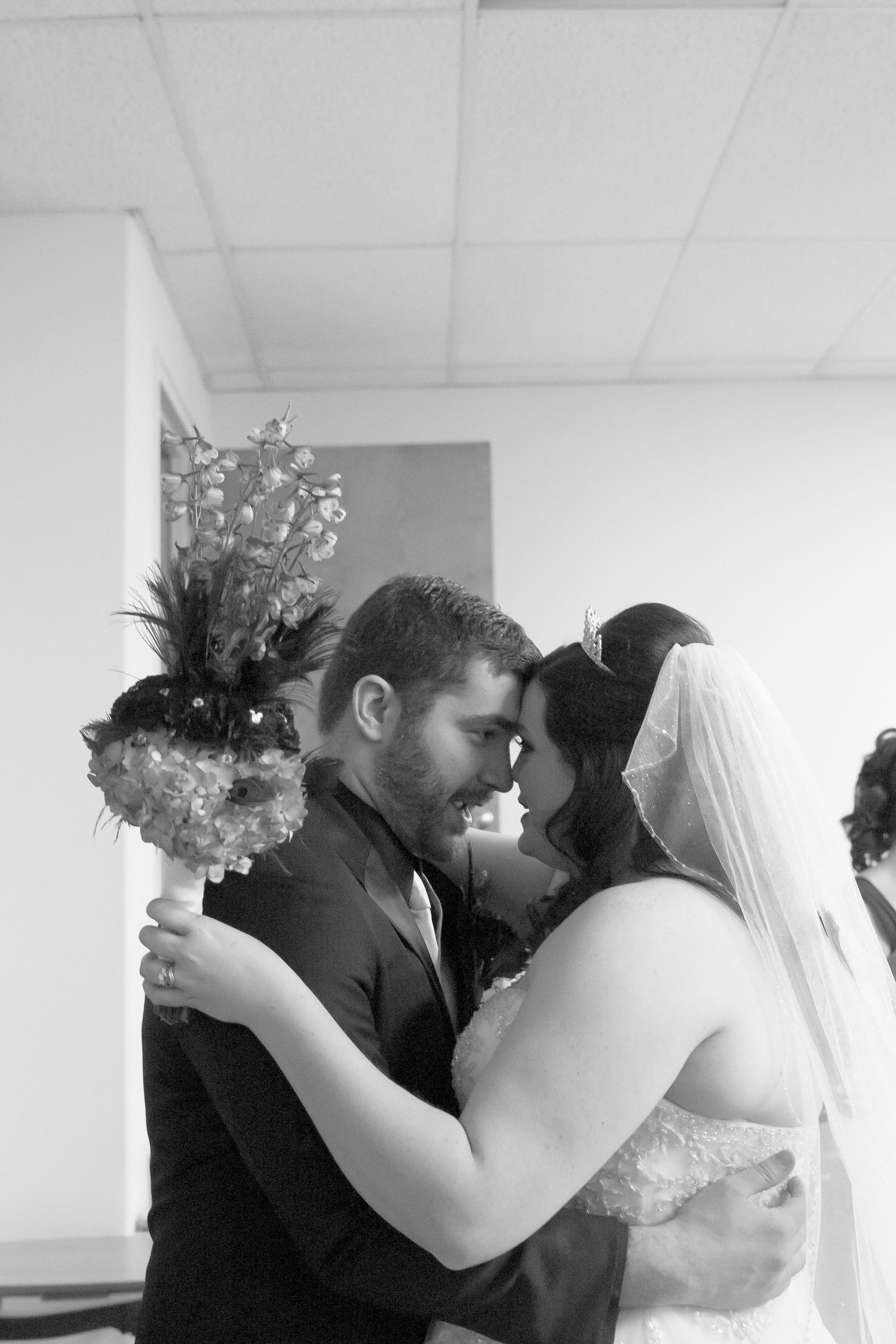 Black and white intimate moment between newlyweds with bouquet.