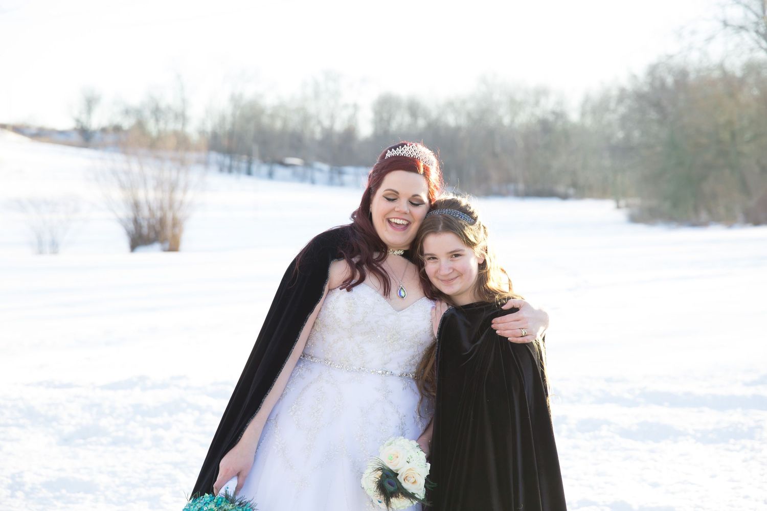 Beautiful winter wedding portrait with bride and companion in black cape.