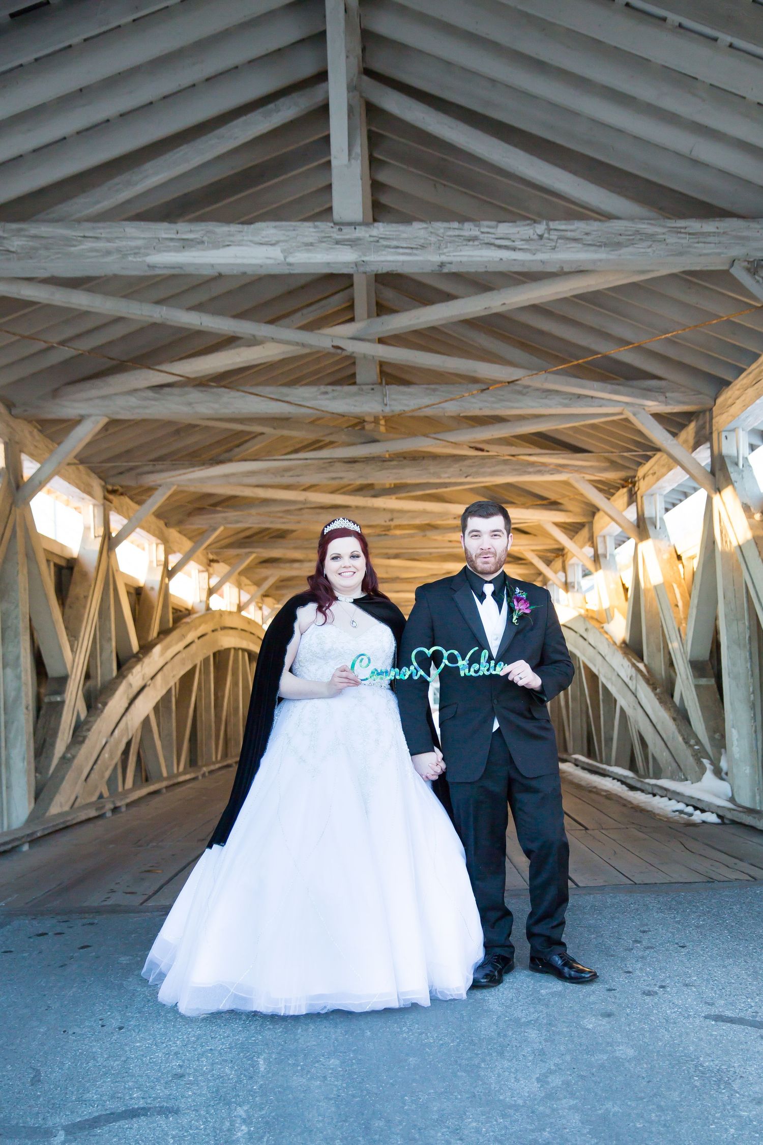 Wedding photo inside covered bridge with wooden beam architecture.