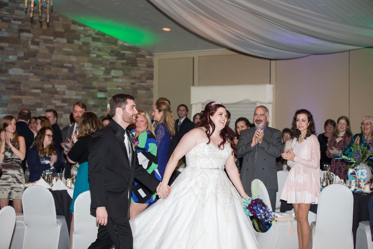 A couple performs their first dance surrounded by guests at their wedding reception.