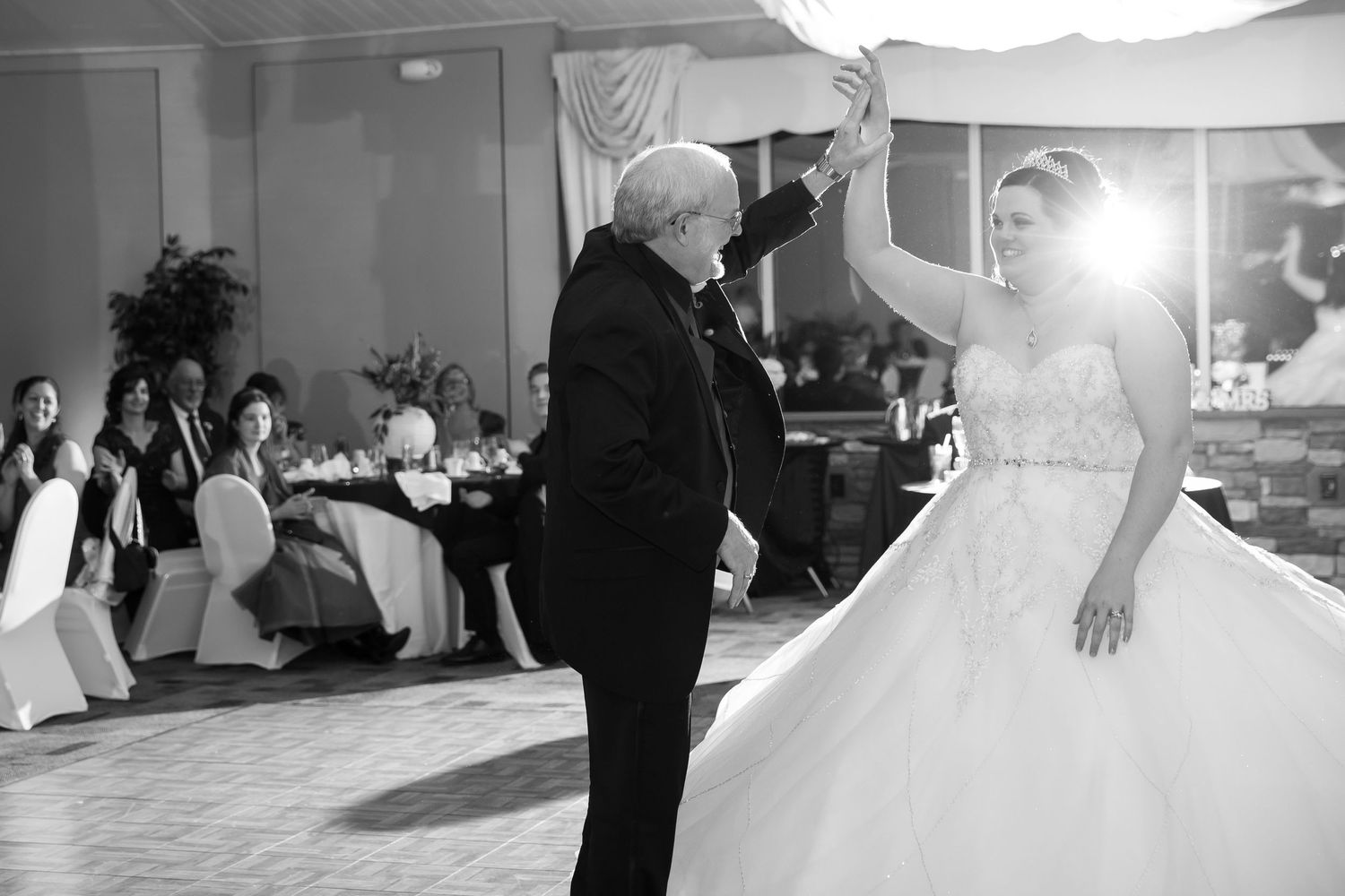 A bride dances in her ballgown during a joyful wedding reception moment.