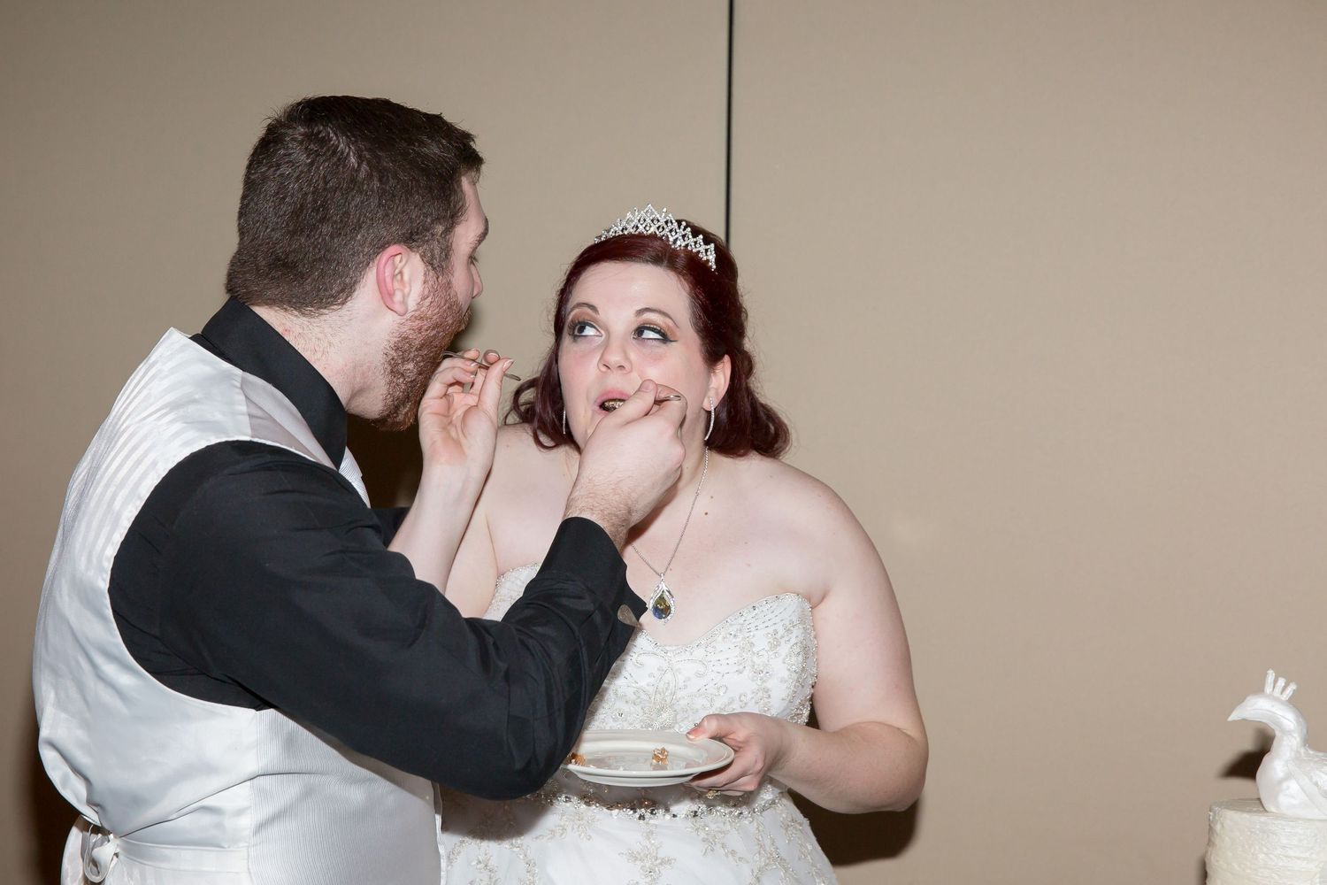 Wedding couple shares a playful moment while feeding each other cake.