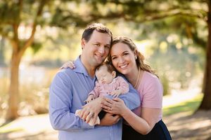 Happy family enjoying a sunny outdoor moment together in a park setting.