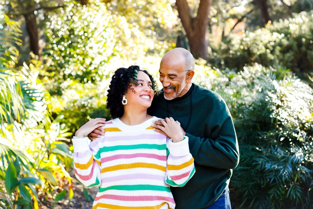 Happy Black couple laughing together outdoors surrounded by lush green tropical plants.