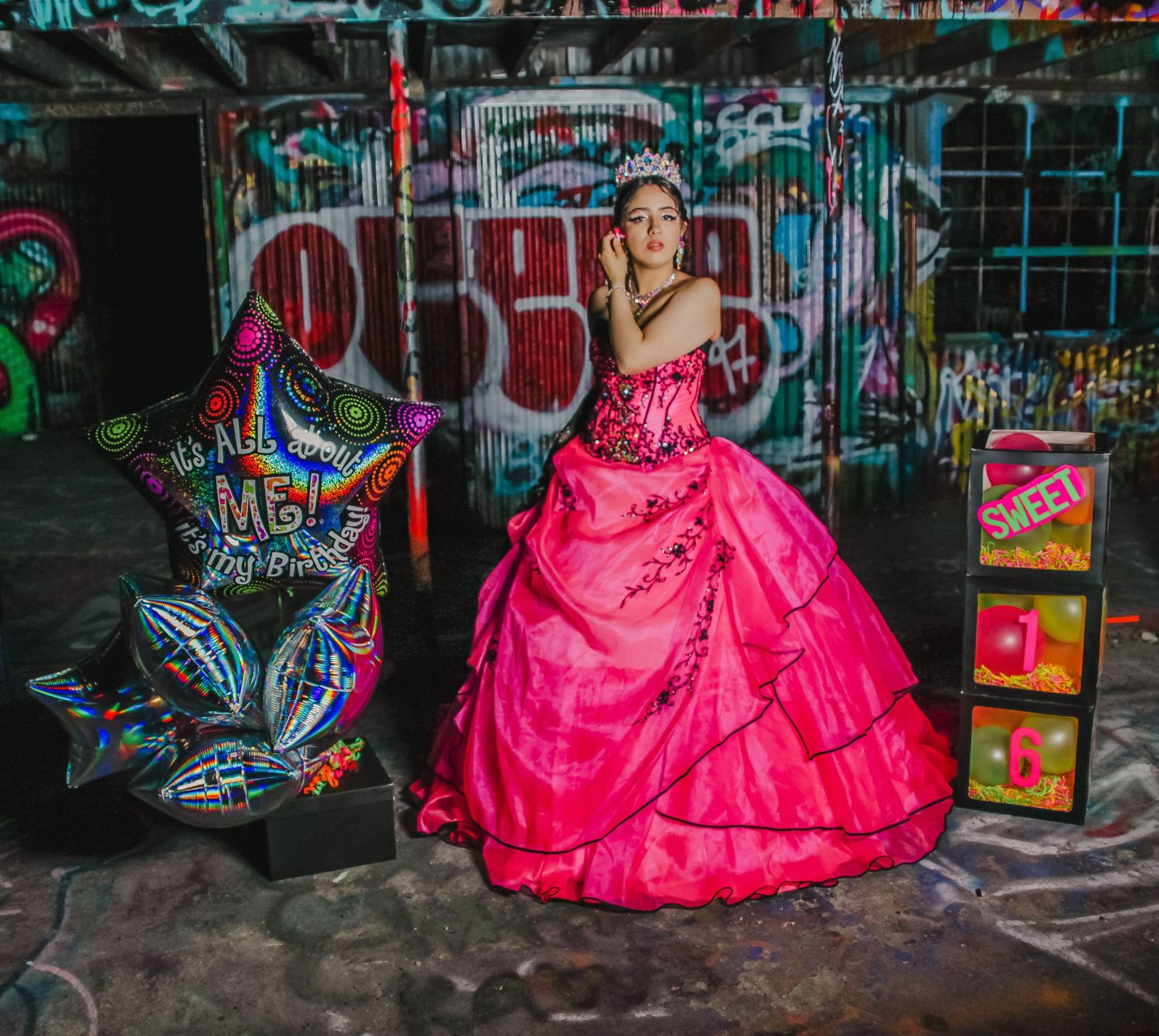 A vibrant pink quinceañera dress photographed against urban graffiti backdrop.