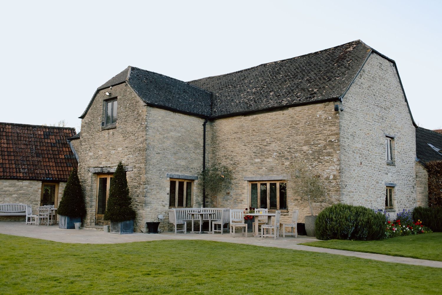 A rustic stone barn venue with outdoor seating area and manicured lawn.