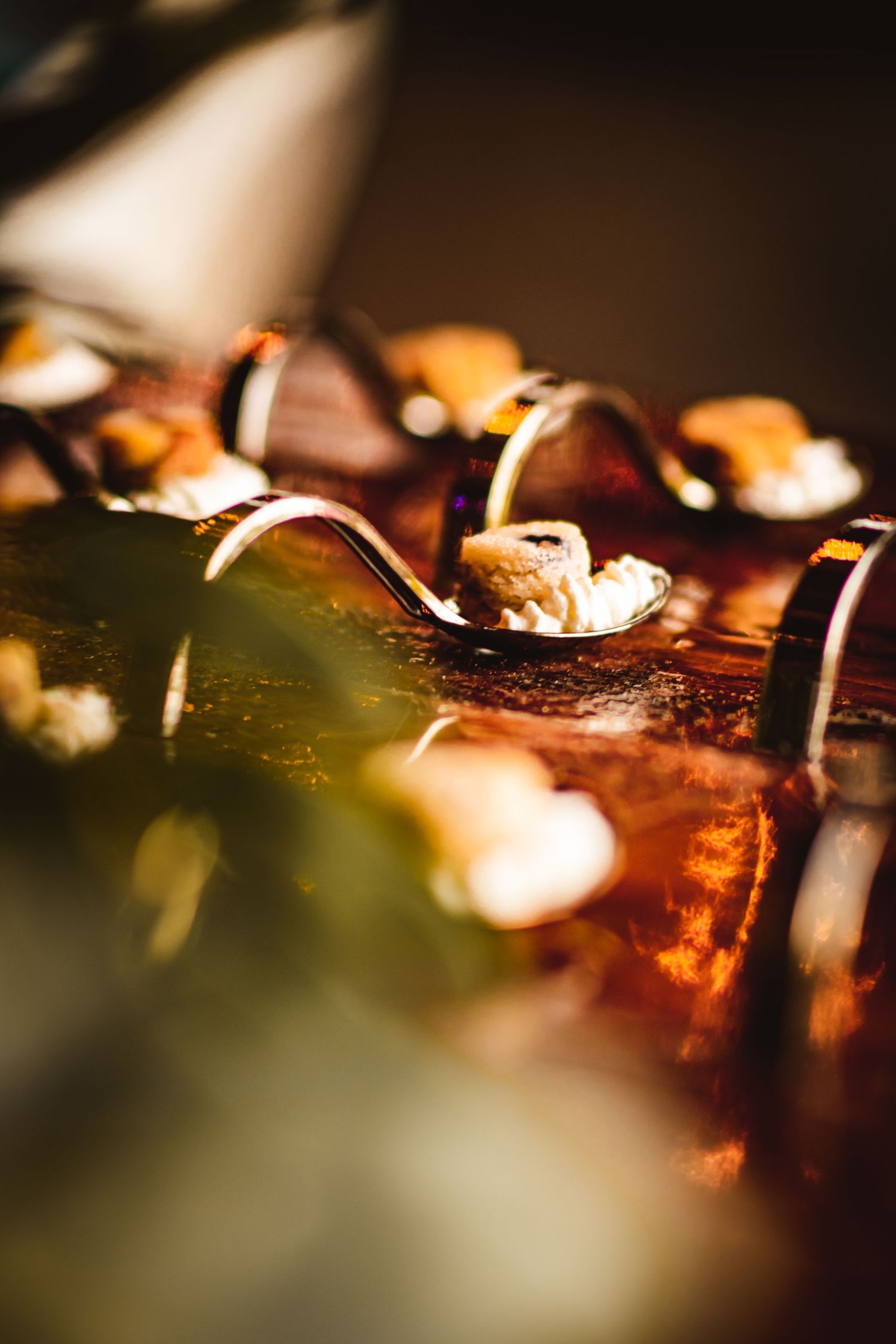 Close-up of elegant wedding appetizers served on decorative spoons in warm lighting.