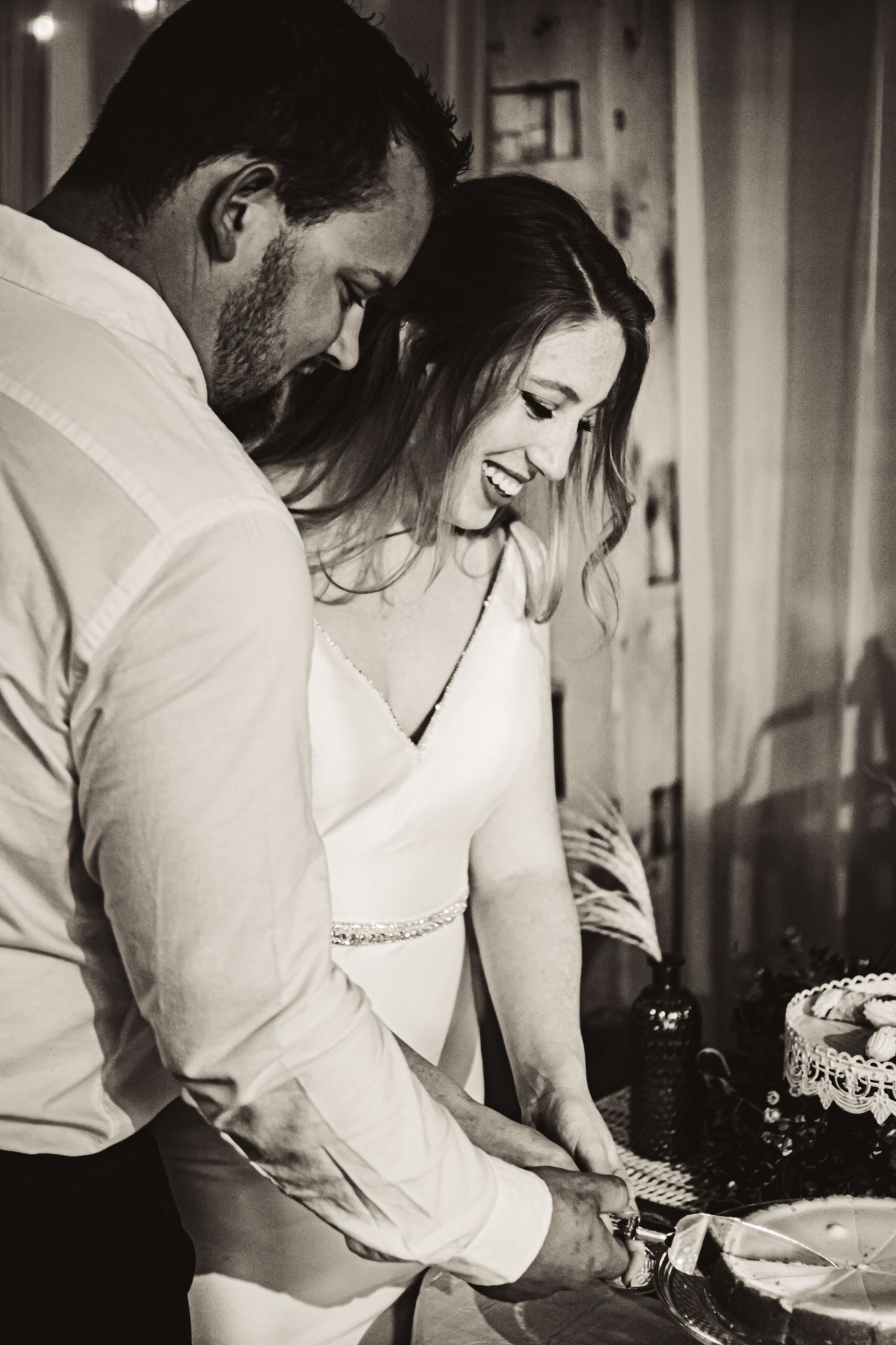 Black and white photo of a couple cutting their wedding cake together.