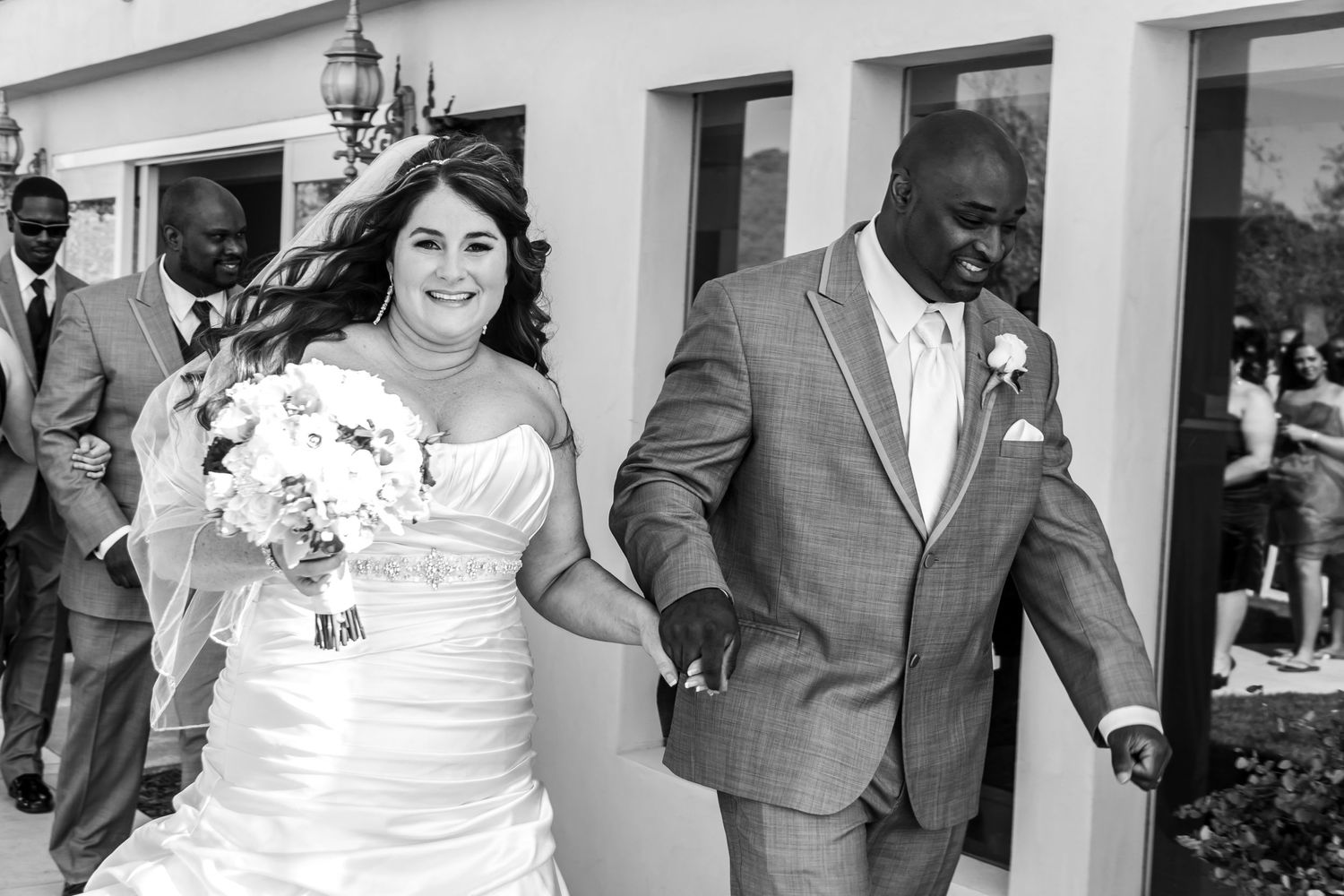 Wedding party members celebrate and dance together during a joyful reception outdoors.