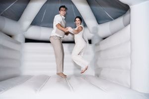 Photo of bride and groom jumping in a bounce house by Anguelo Photography