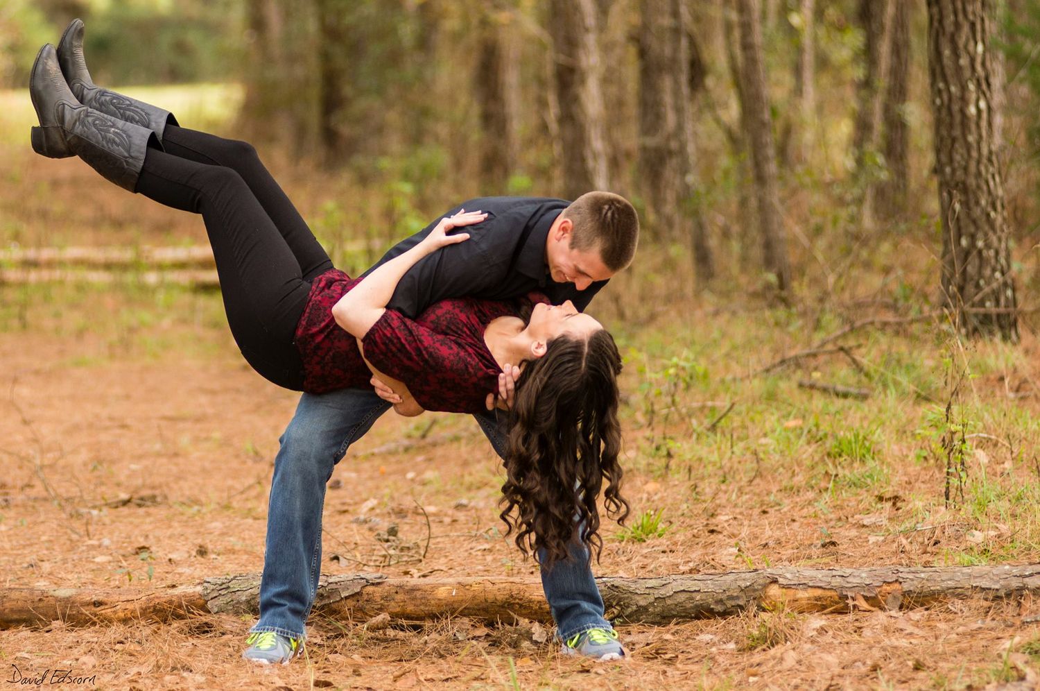 Playful couple dancing in a forest setting with a dramatic dip pose.