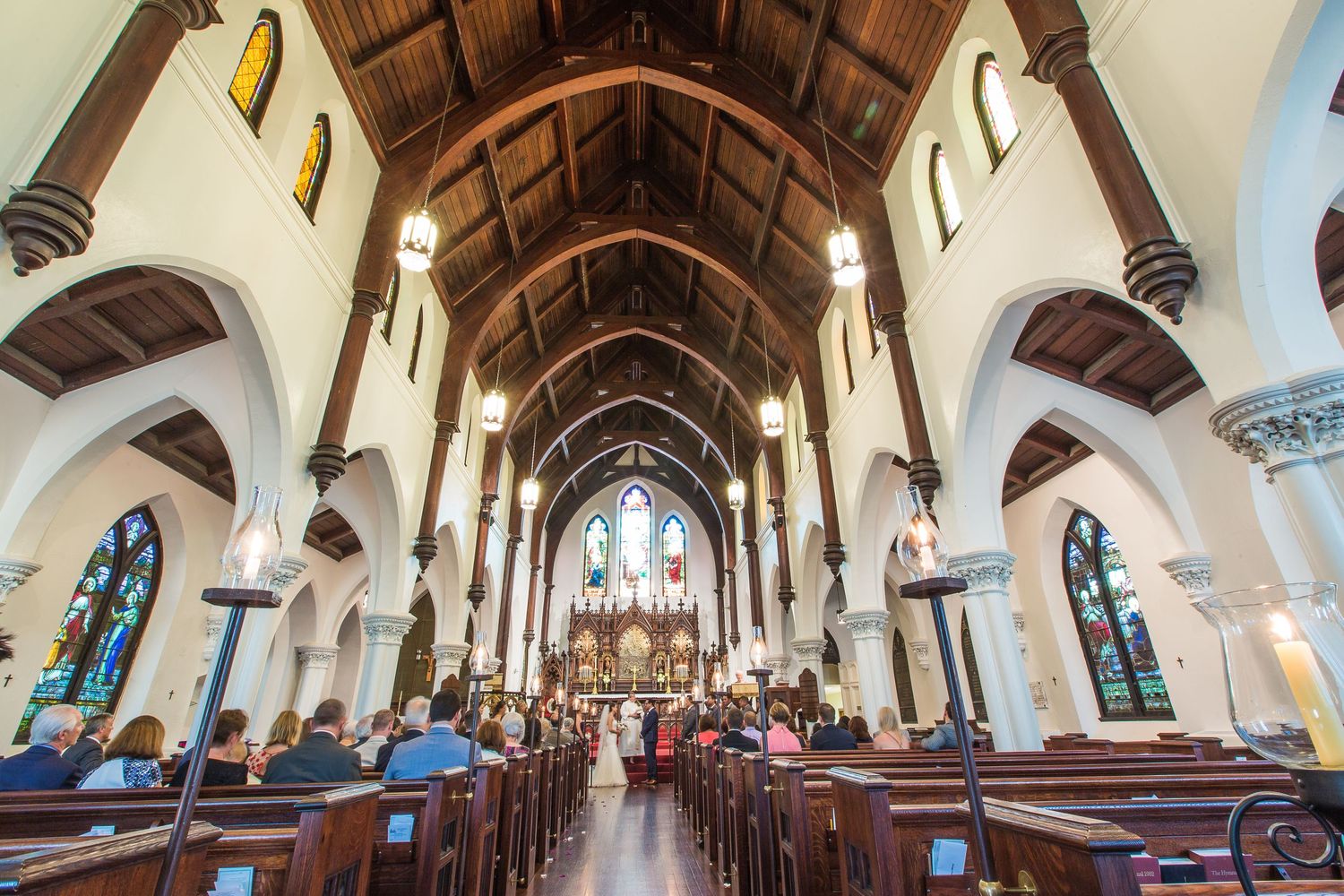 Interior of Gothic church with wooden arched ceiling and stained glass windows.
