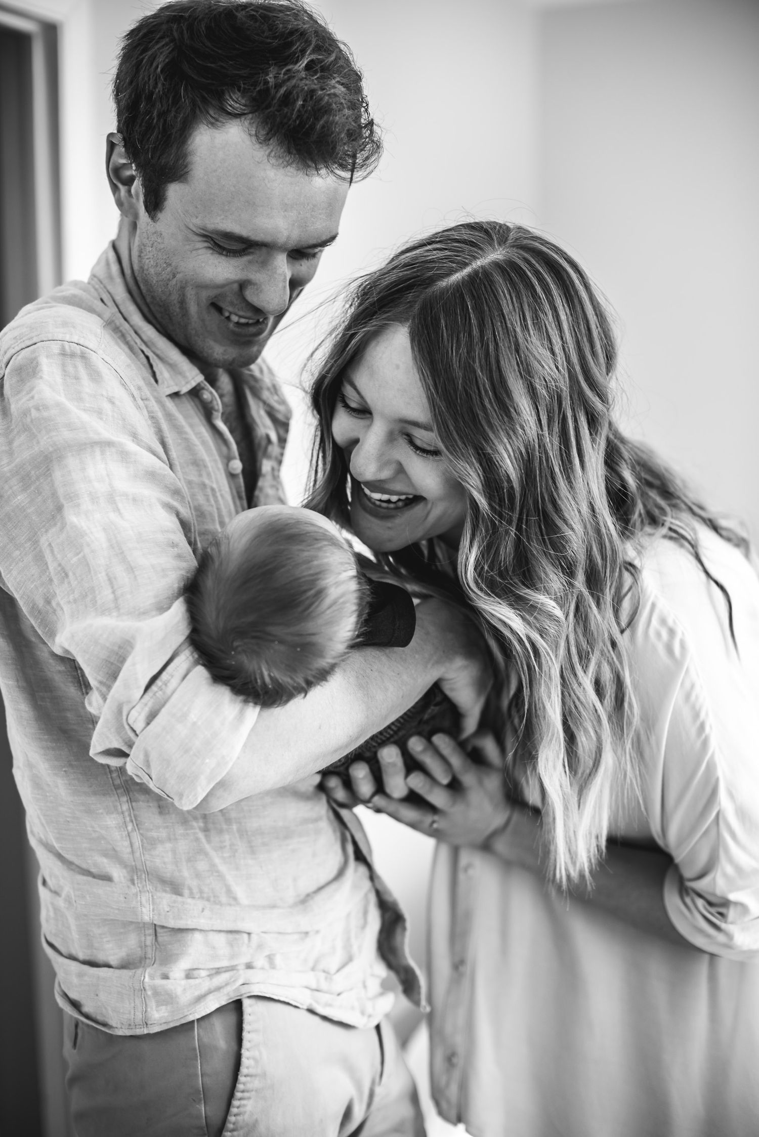 A man holds his newborn child as mother smiles with her full heart.