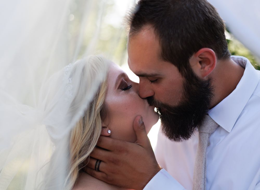 A tender wedding kiss moment captured in soft natural light.