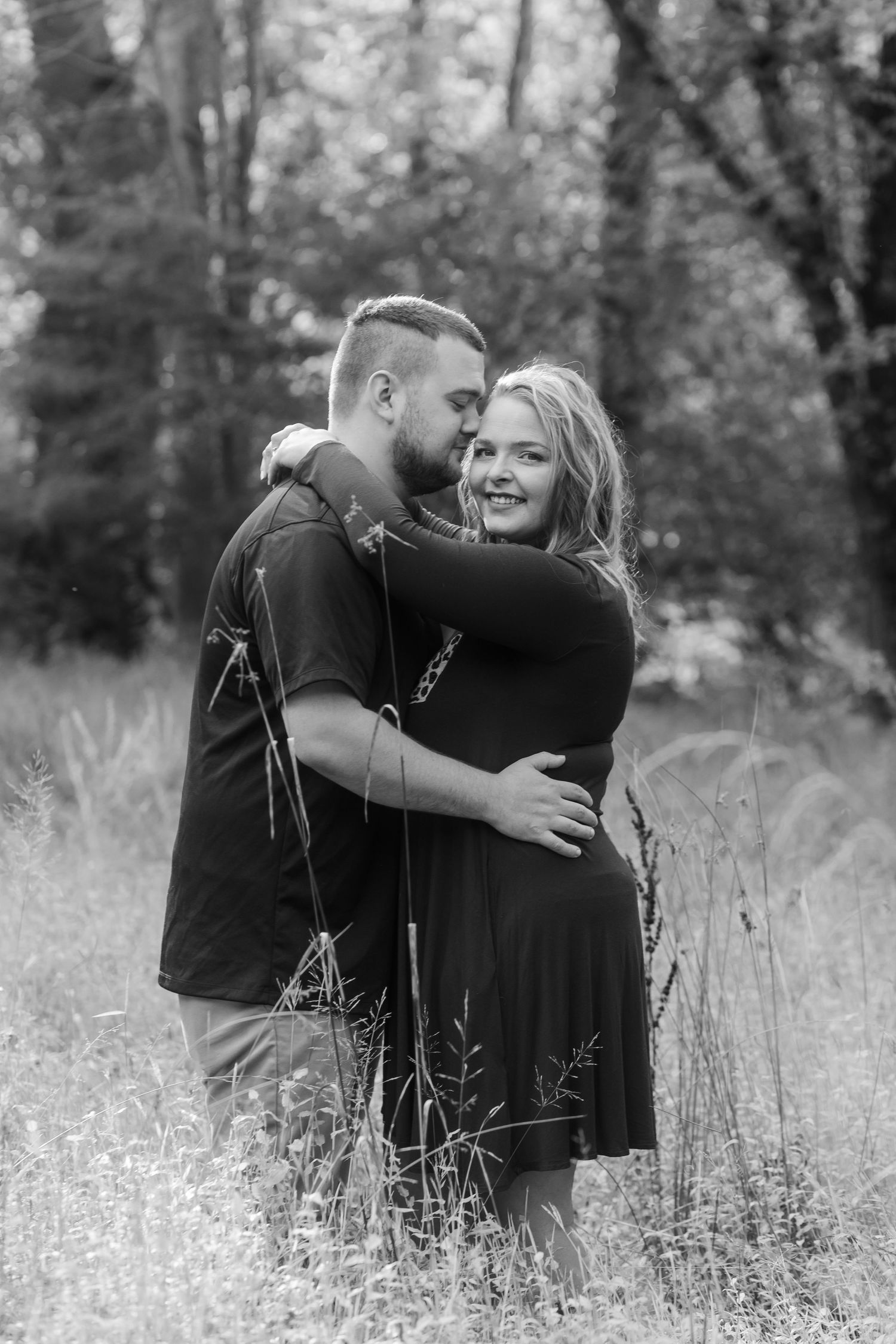Black and white portrait of a couple embracing in a field of wildflowers.