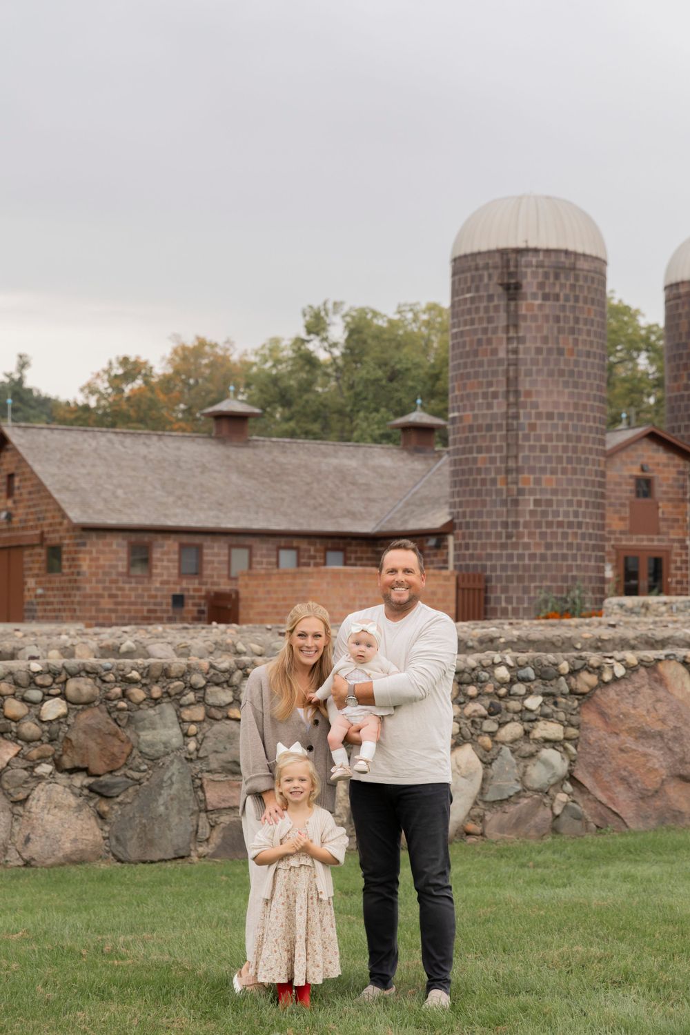 family of four with two little girls smiling for a photo at Rochester Hills museum at van hoosen farm
